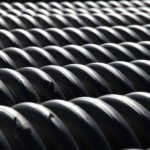 photos of a stack of corrugated black pipe in a construction area