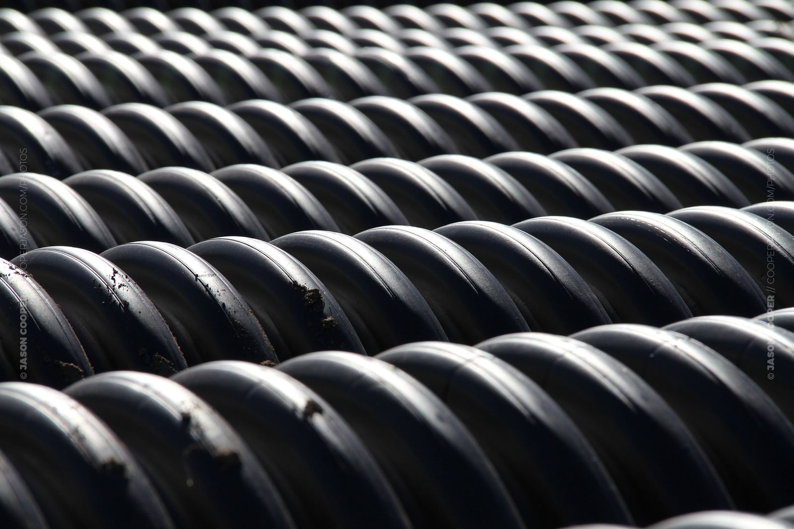 photos of a stack of corrugated black pipe in a construction area