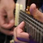 close up photo of musicians hand playing a worship team guitars